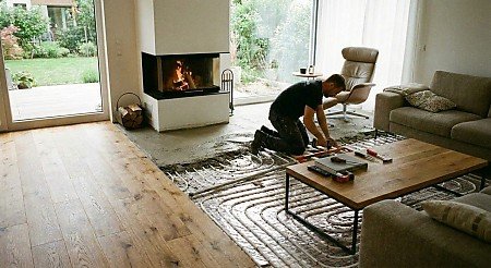 Handwerker verlegt Fußbodenheizung